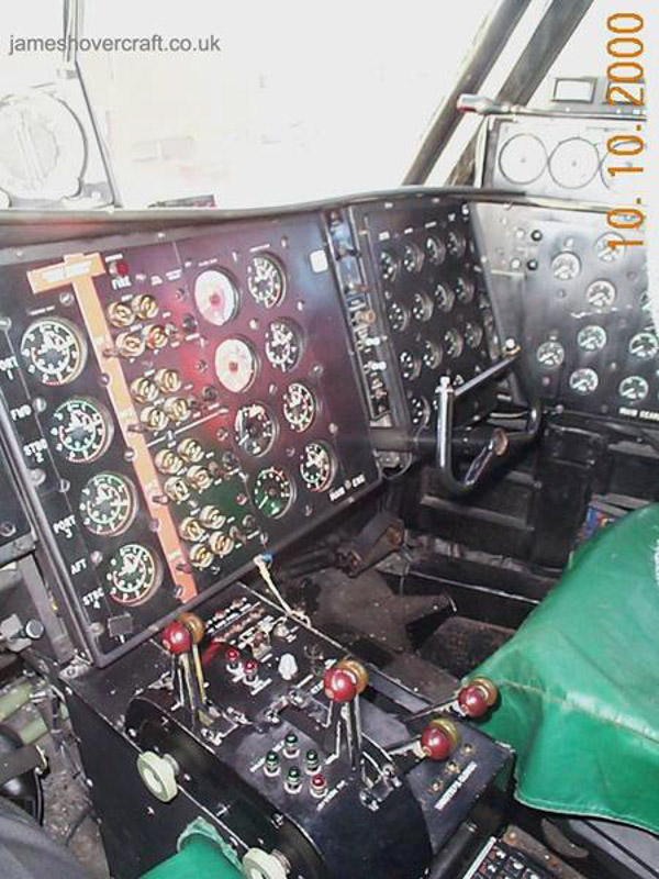 SRN4 systems tour - Here a view of the control cabin as seen from the pilot's seat, you can see the control column - with four degrees of motion: left & right controlling pylon movement (+/- 30° from normal), in and out controlling hoverheight and propeller pitch amount interchangeably. <br><br>Also seen are eight red/brown levers. These control, from left to right: Propeller pitch on each propeller: Positive, Zero and Negative; Engine throttle from idle to full power. A selection switch also exists to control whether all four pylons would move synchronously, or whether just the rear two pylons would swivel. <br><br>At the bottom of the two foot wells are the rudder pedals, controlling the angles of the two rear fins to the airflow. <br><br>The pilot and first officer's control column and rudder pedals are mechanically linked to each other, guaranteeing synchronous operation at all times. <br><br>More detail on each of these controls is on the Cockpit Tour page.  (submitted by James Rowson).